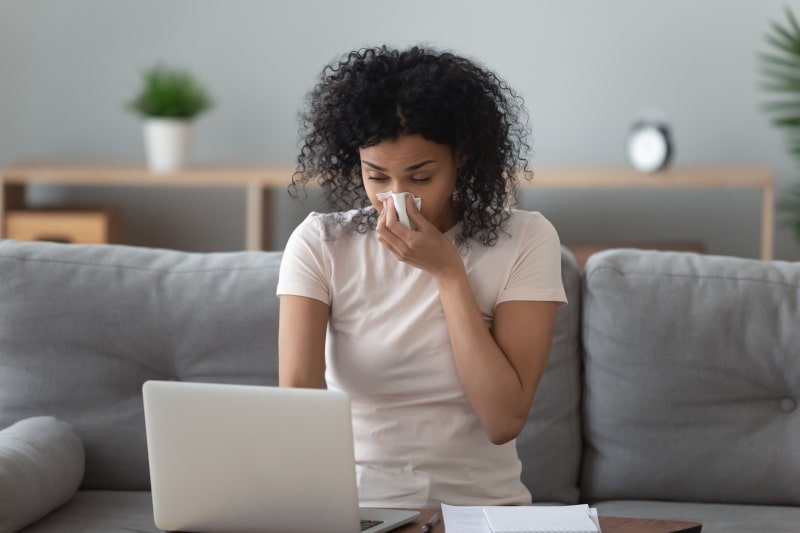 Woman in living room blowing nose